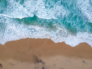 Sand beach aerial, top view of a beautiful sandy beach aerial shot with the blue waves rolling into the shore