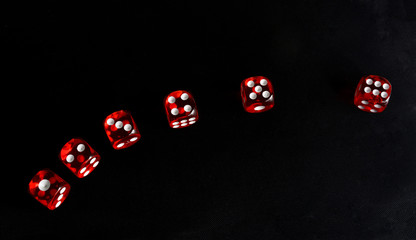 Six red dice with white points on the black table.