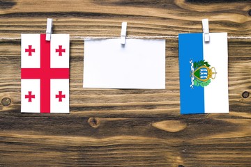 Hanging flags of Georgia and San Marino attached to rope with clothes pins with copy space on white...