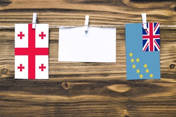 Hanging flags of Georgia and Tuvalu attached to rope with clothes pins with copy space on white...
