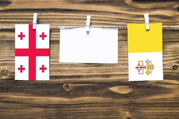 Hanging flags of Georgia and Vatican City attached to rope with clothes pins with copy space on...