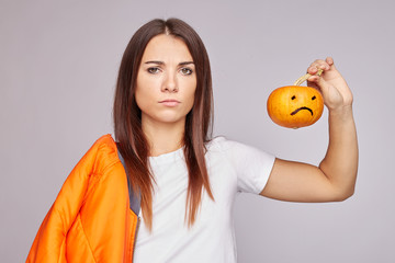 Discontent office worker frowns face, looks at camera, dressed in casual white t-shirt, isolated with free space over grey studio wall, advertises something negative. Bad emotions and feelings concept