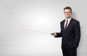 Young businessman with laser pointer and copyspace white wall