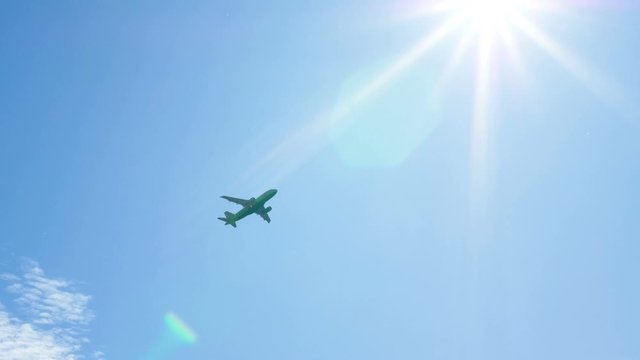 Large passenger plane gaining altitude after takeoff in front of the bright sun