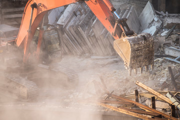 construction site, excavator bucket destroys an old building on site