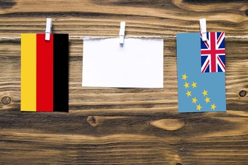 Hanging flags of Germany and Tuvalu attached to rope with clothes pins with copy space on white...