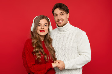 smiling young couple holding hands isolated on red background. Christmas concept