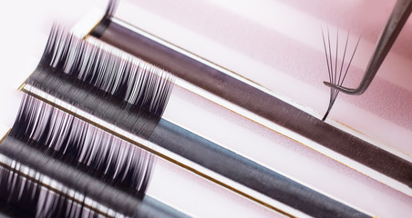 Eyelash extension procedure. Lashes set macro photo, pink background