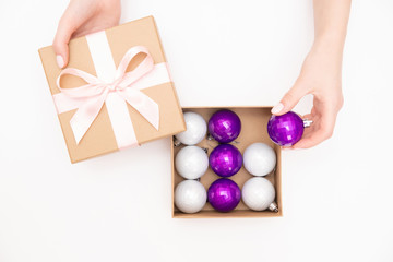 Girl opened box with New Year balls bubbles for Christmas tree, white background