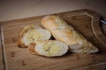 Tasty garlic bread, baguette on kitchen board