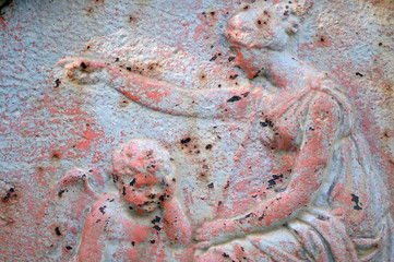 A weathered, rusted metal sculpture. A woman consoling a grieving angel.