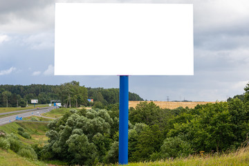 White blank billboard template along highway against fields
