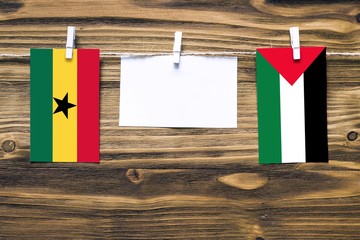 Hanging flags of Ghana and Palestine attached to rope with clothes pins with copy space on white...