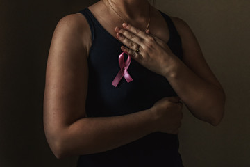 October is breast cancer awareness month,a woman holds a pink ribbon to support people living and...