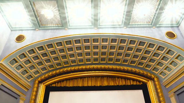 Tilt-up over large interior of vintage movie theater cinema with white empty screen with large copy space waiting for the premiere of the latest blockbuster movie