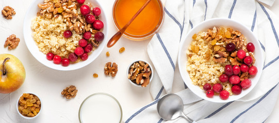Tasty and healthy breakfast. Bulgur porridge with berries, honey and walnuts on a light background, top view. Healthy vegetarian food.