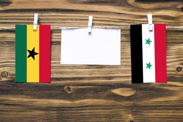 Hanging flags of Ghana and Syria attached to rope with clothes pins with copy space on white note...