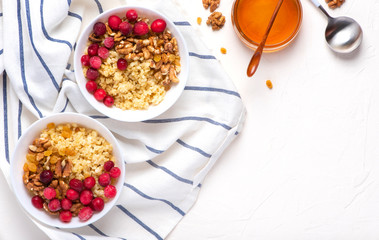 Tasty and healthy breakfast. Bulgur porridge with berries, honey and walnuts on a light background, top view. Healthy vegetarian food.