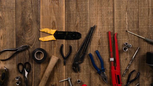 Animation of a hand tool on a wood table, logo intro stop motion. The concept of a set of tools for repair. Top view of hammer, screwdriver and other hand tool on wooden board for home craftsman.