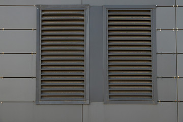 Front view of dirty dark grey ventilation grill in matte metal wall