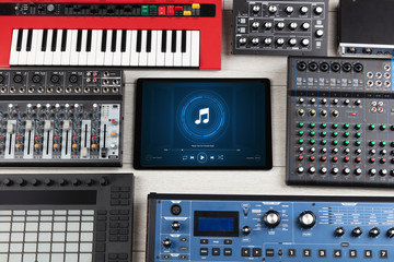 Playing song on tablet with electronic music instruments around