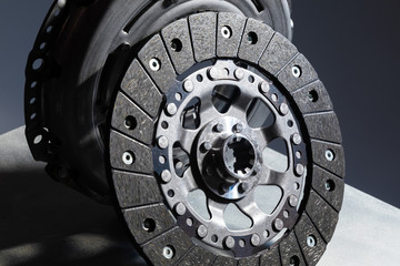 Close-up picture of a part of car, black clutch disk isolated on black background with light - obrazy, fototapety, plakaty