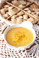Obraz na płótnie Canvas Pumpkin cream spiced with curry in a white bowl and some roasted pumpkin dice and croutons. Close Up