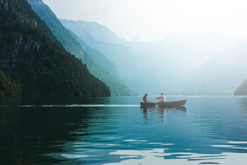 Loving young couple in boat at lake. Date walk man and woman in alpine mountains - Powered by Adobe