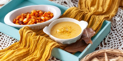 Pumpkin cream spiced with curry in a white bowl with roasted pumpkin and bread. Close Up