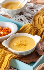Pumpkin cream spiced with curry in a white bowl with roasted pumpkin and bread. Close Up