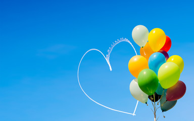 Colorful balloons and heart written in the sky by aircraft