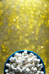 Top view of a blue plate with marshmallows on a beautiful blurry background. Christmas composition with sweets.