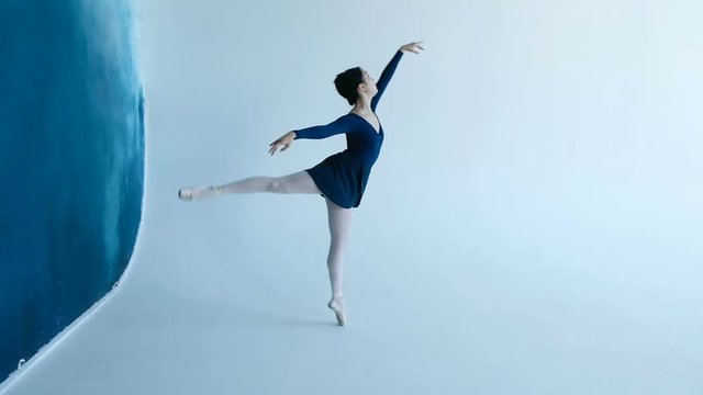 Professional young ballerina dancing on white background in slow motion