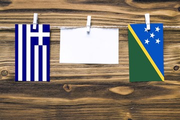 Hanging flags of Greece and Solomon Islands attached to rope with clothes pins with copy space on...