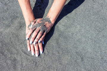 girl's hand on a background of black sand.