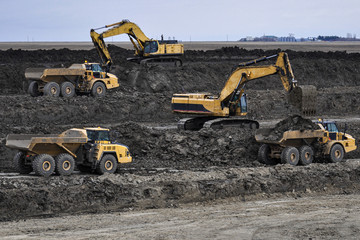 Excavators loading rock trucks with earthen fill material to be used for the construction of highway interchange bridge embankments © Randy