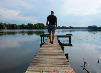 Back view of boy with casual clothing on wooden pier. summer day. Concept freedom