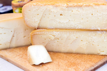 hard cheeses sliced on a wooden board on a dark rustic background