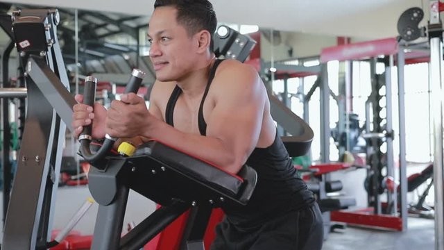 Muscular man doing abs exercise on abdominal coaster gym machine