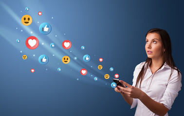 Young person using smartphone with flying social media icons around