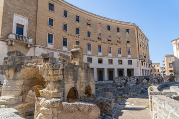 Roman Amphitheatre in Lecce, Puglia (Apulia), southern Italy. Ruins of a Roman amphitheater. INA (Istituto Nazionale Assicurazioni) Building behind.