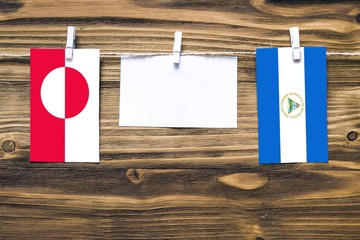Hanging flags of Greenland and Nicaragua attached to rope with clothes pins with copy space on...