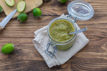 Fresh feijoa jam in a glass jar on the wooden background