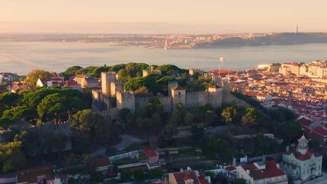 Lisbon, Portugal. Aerial view of the Sao Jorge Castle (Castelo de S&atilde;o Jorge), with 25 de Abril Bridge (Ponte 25 de Abril, 25th of April Bridge) on the background at dawn