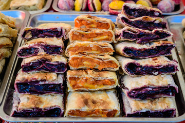 Fresh homemade sour cherries and pumpkin pie pieces displayed for sale at a street food market, side view of healthy food photograph with soft focus