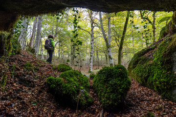 cueva en mitad de un bosque con una chica caminando