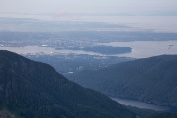 Aerial View of Grouse Mountain with Downtown City in the background during a sunny and hazy summer day. Taken in North Vancouver, BC, Canada.