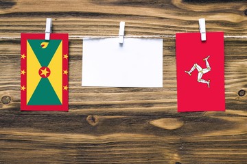 Hanging flags of Grenada and Isle Of Man attached to rope with clothes pins with copy space on...