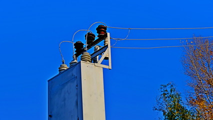 The pillar is electric. Electric wires. Power lines. Crows on wires
