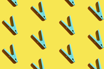 Blue clothespins pattern on yellow background, flatlay.